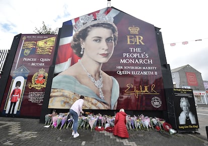 Varias personas colocan ramos de flores en un mural con la imagen de Isabel II en una calle en Belfast, este viernes. Se espera que el nuevo rey se reúna con la dirigente tory a su llegada a Londres, así como con el conde mariscal, Edward Fitzalan-Howard, la persona encargada de preparar la proclamación y el funeral de su madre, a fin de aprobar el calendario programado para los próximos días.