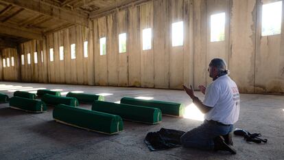 Un hombre reza ante varios ataúdes en la antigua base de la ONU en Potocari, cerca de Srebrenica.