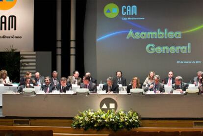 El presidente de Banco Base, Modesto Crespo, en el centro, y a su izquierda la directora general de la CAM, María Dolores Amorós, en la asamblea de la entidad, ayer en Alicante.