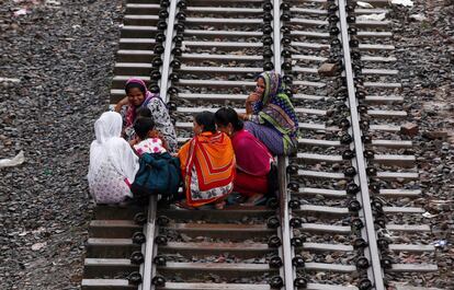 Unas mujeres en Bangladesh esperan en las vías del ferrocarril a que pase un tren de pasajeros para viajar a casa para celebrar el Eid al-Fitr festival, que marca el final del mes de ayuno del Ramadán.