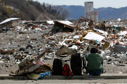 Una mujer con sus pertenencias, entre los escombros de su casa destruida en Yamada, en la prefectura de Iwate.