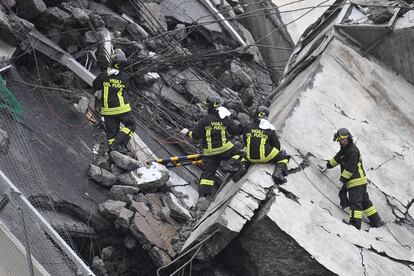 Miembros de los servicios de emergencia buscan entre los escombros tras derrumbarse una sección del viaducto Morandi en Génova (Italia).