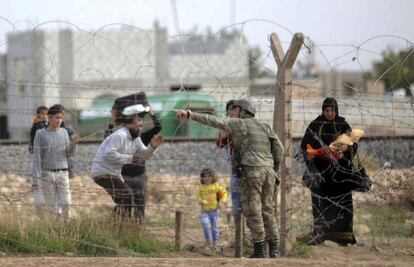 Soldados turcos hablan con civiles sirios en el puesto fronterizo de Ceylanpinar.