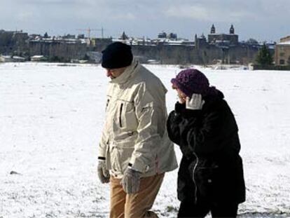 Una pareja camina en Pamplona, donde la ola de frío ha cubierto la ciudad de una espesa capa de nieve.