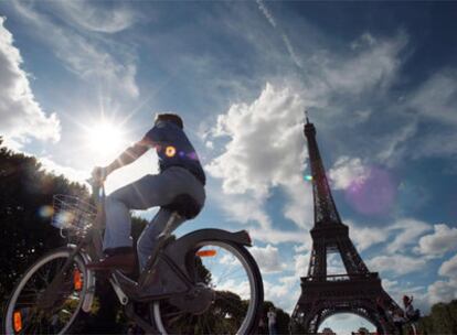 Un turista pasea en bici bajo la Torre Eiffel de París