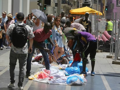 Los manteros recogen sus sábanas delante de un conocido comercio de Gran Vía.