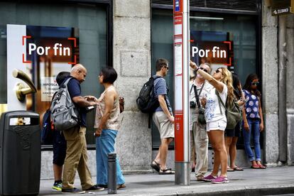 Turistas esperan en una parada de autobús en el centro de Madrid.