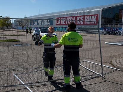 Dos operarios colocan una verja en el exterior del Palacio de Hielo de Majadahonda, este viernes.