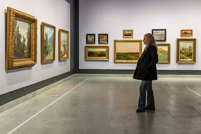 Una persona observa algunas de las pinturas que forman parte de la exposición.