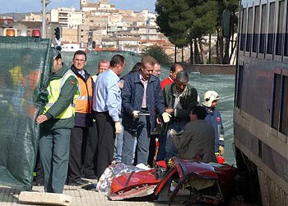 Agentes de policía de Albacete examinan los restos del  vehículo arrollado por un tren en un paso a nivel en Hellín.