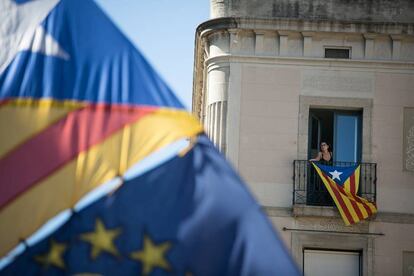 Una mujer se asoma por el balcón de su casa donde cuelga una bandera estelada en la plaza Sant Jaume.