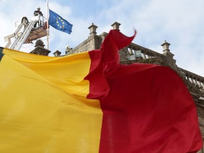 Un bombero coloca a media asta la bandera europea en el Ayuntamiento de Santiago de Compostela, mientras la bandera belga ondea tambi&eacute;n en la plaza del Obradodoiro, momentos antes del minuto de silencio guardado en memoria a las v&iacute;ctimas de los atentados cometidos ayer en B&eacute;lgica. 