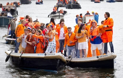 Cientos de personas con camisetas naranjas celebran la investidura del rey Guillermo de Holanda en uno de los canales de Ámsterdam.