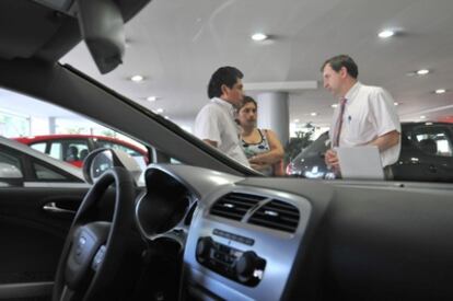 Un vendedor conversa con dos clientes en un concesionario.