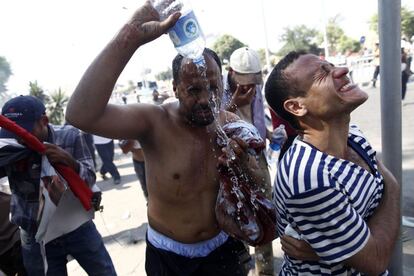 Partidarios de Morsi se limpian la cara tras ser gaseados por el ejército egipcio durante las protestas en el exterior de la sede de la Guardia Republicana en el Cairo, 5 de julio de 2013. El líder de los Hermanos Musulmanes, Mohamed Badía, dijo que seguirán manifestándose hasta que vuelva al poder el depuesto presidente egipcio, Mohamed Mursi, e instó al Ejército a que lo restituya en el cargo.