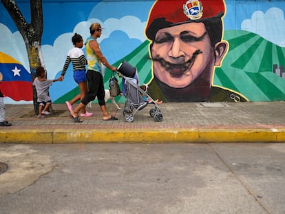 Una familia camina frente a un mural con el rostro del expresidente Hugo Chávez, este lunes en Caracas.