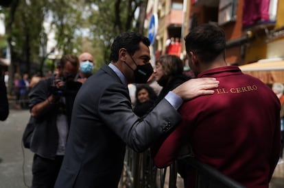 El presidente de la Junta de Andalucía, Juan Manuel Moreno, conversa con un costalero de la Hermandad del Cerro del Águila, el Martes Santo en Sevilla.