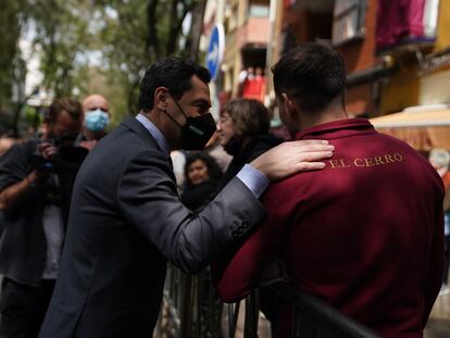 El presidente de la Junta de Andalucía, Juan Manuel Moreno, conversa con un costalero de la Hermandad del Cerro del Águila, el Martes Santo en Sevilla.