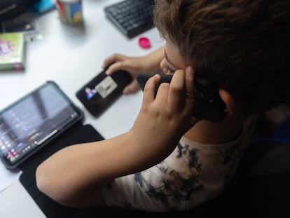 Un niño usa el teléfono móvil y y un dispositivo electrónico.