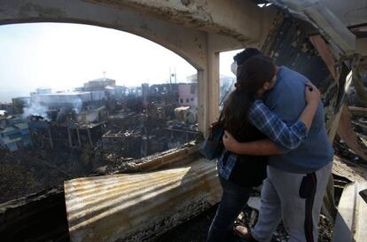 Um casal se abraça na frente da janela de casa.