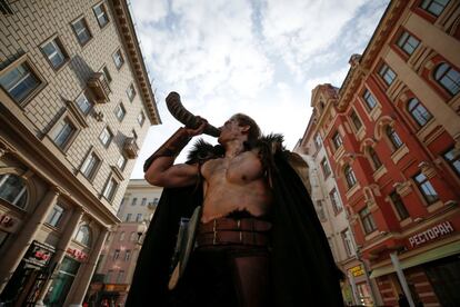 Un hombre vestido de vikingo sostiene un cuerno en una calle en el centro de Moscú, Rusia.