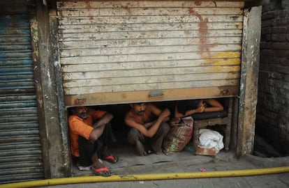 Tres personas miran la llegada de Valerie Trierweiler, la expareja del presidente francés, François Hollande, durante su visita a la zona de Ekta Nagar en Bombay (India).