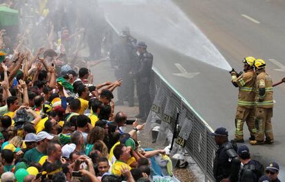 Una pareja de bomberos refresca al público que se congrega frente al Palacio Planalto para presenciar la investidura de Bolsonaro.