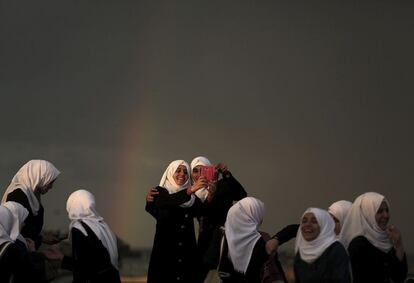 Estudiantes palestinas posan para un selfi con el arcoiris de fondo durante un día lluvioso en la Franja de Gaza.