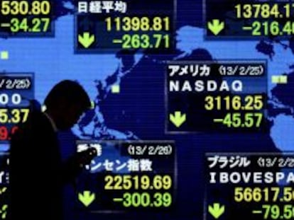 Un peat&oacute;n camina junto a una pantalla informativa que muestra los datos de la Bolsa de Tokio. 