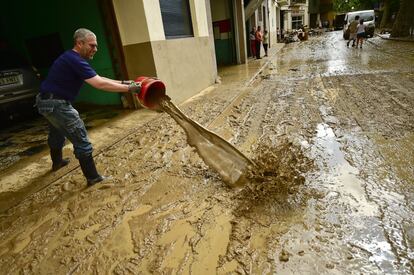 Un vecino retira restos de agua y barro con un cubo tras las riadas que han afectado a la localidad navarra de Tafalla.