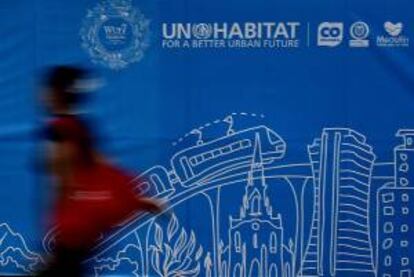 Una mujer camina frente a un cartel alusivo al Foro Urbano Mundial en Medellín (Colombia).