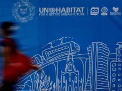 Una mujer camina frente a un cartel alusivo al Foro Urbano Mundial en Medellín (Colombia).