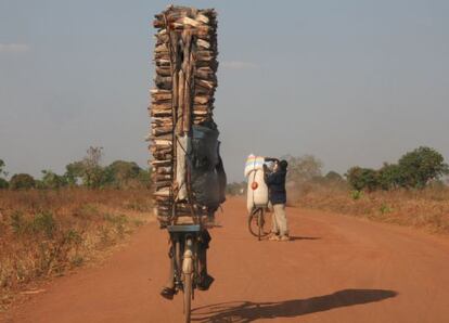 Joven trasladando maderos en su bicicleta en Malawi.