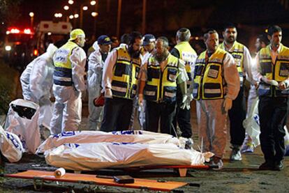 Equipos de rescate observan los cuerpos, envueltos en bolsas, de dos personas asesinadas en el atentado de ayer.