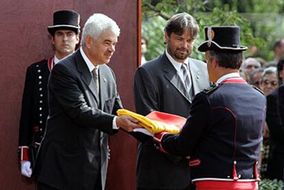 Maragall, junto a Benach, entrega la <i>senyera</i> al jefe de la formación de los Mossos d'Esquadra durante el acto de ayer en el parque de la Ciutadella.