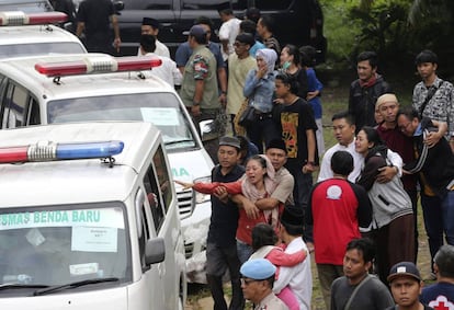 Familiares de las víctimas del accidente en Java este sábado, junto a varias ambulancias.