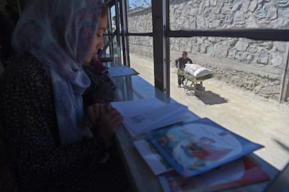 Un niño lleva una carretilla mientras una joven lee un libro en una biblioteca-autobús, en Kabul (Afganistán).