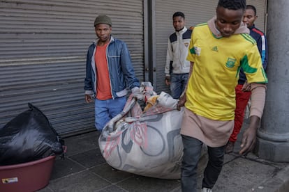 Varios residentes del edificio afectado por las llamas trasladan sus pertenencias.