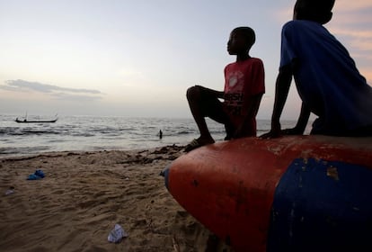 Dos niños observan la playa del municipio de West Point (Liberia) mientras descansan en una barca.