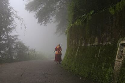 Un tibetano exiliado en la India camina bajo la lluvia durante una ola de tormentas monzónicas en McLeod Ganj, cerca de Dharamsala.