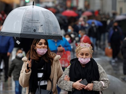 Varias personas caminan con mascarillas por la calle Preciados durante las Navidades, en plena explosión de la sexta ola de covid en España.