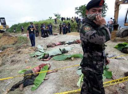 Un policía, junto a varios cadáveres hallados ayer en una fosa común en la localidad filipina de Ampatuan (Maguindanao).