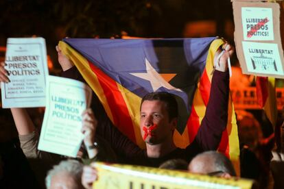 Un joven con la boca tapada sostiene una bandera independentista mientras participa en una concentración frente al Parlament.