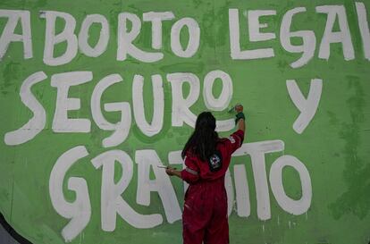 Una mujer pinta un mural a favor del aborto legal y gratuito durante las protestas de este martes en Santiago de Chile. La iniciativa legislativa aprobada modifica el Código Penal, pero todavía falta redactar el articulado y discutirlo luego en el Senado.