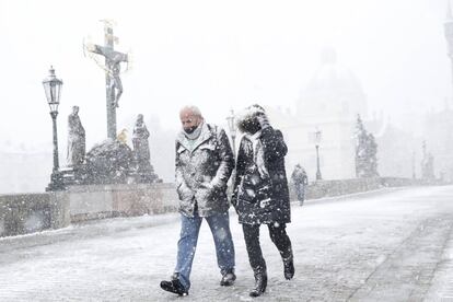 Dos personas cruzan el puente medieval de Carlos durante una intensa tormenta de nieve, en Praga, República Checa.