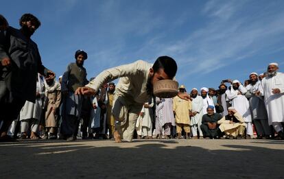 Un partidario del partido religioso y político Jamiat-Ulema-e-Islam (JUI-F) juega 'topai' (gorra), un juego tradicional que consiste en elegir una gorra con la boca mientras se balancea sobre un dedo del pie, durante el llamado Azadi March (Freedom March), convocada por la oposición, para protestar contra el gobierno del primer ministro Imran Khan en Islamabad (Pakistán).