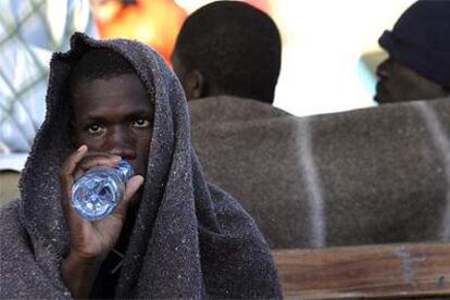 Un inmigrante bebe agua mientras descansa a su llegada al puerto de Los Cristianos (Tenerife).