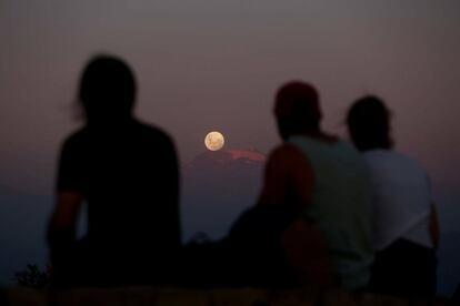 Un grupo de personas observa la superluna subiendo tras la cordillera de Los Andes en Santiago (Chile). 