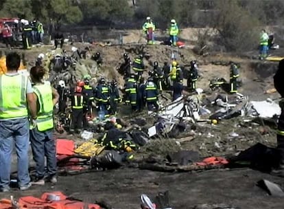 Equipos de bomberos trabajan en el rescate de cadáveres entre fragmentos calcinados del avión siniestrado en Barajas.