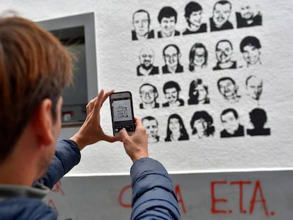 Un hombre hace una foto con su móvil a unas pintadas con las caras de los presos de ETA.